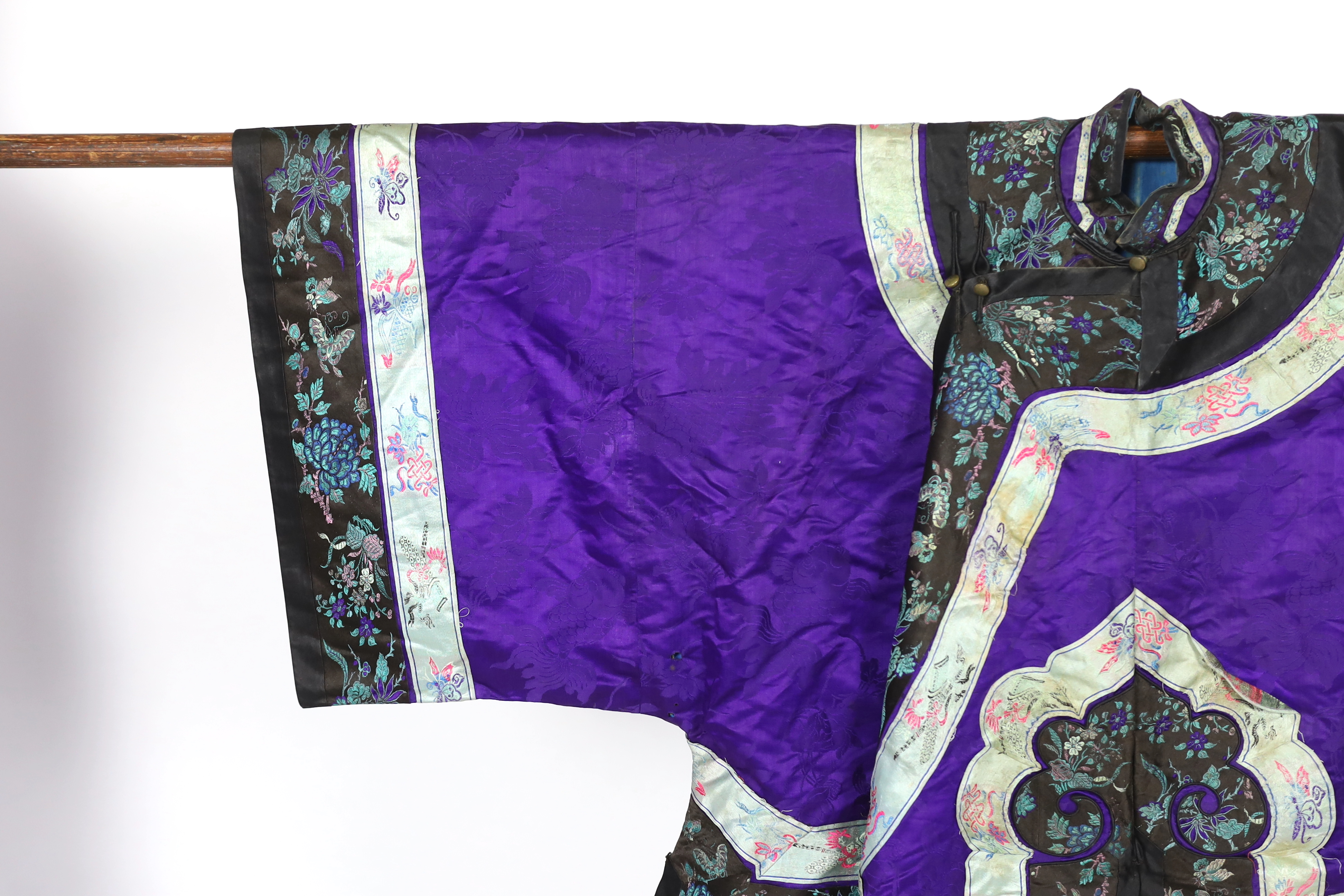 A Chinese purple damask jacket, circa late 19th / early 20th century, decorated with black and turquoise embroidered braiding with auspicious symbols, butterflies and flowers embroidery, 63cm long